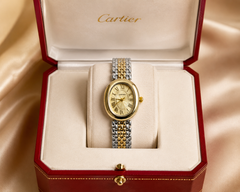 Gold and silver watch in a Cartier box on a beige background