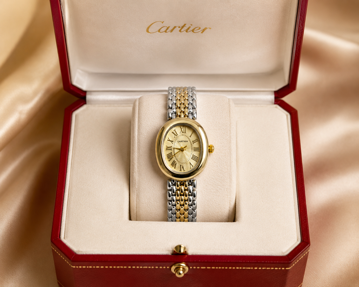 Gold and silver watch in a Cartier box on a beige background